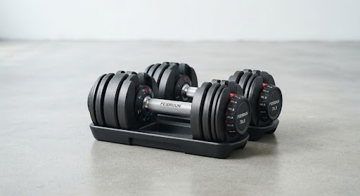 Studio photograph of the FEIERDUN 70lb adjustable dumbbell set on a minimalist concrete floor, highlighting the steel handle and molded weight plates.